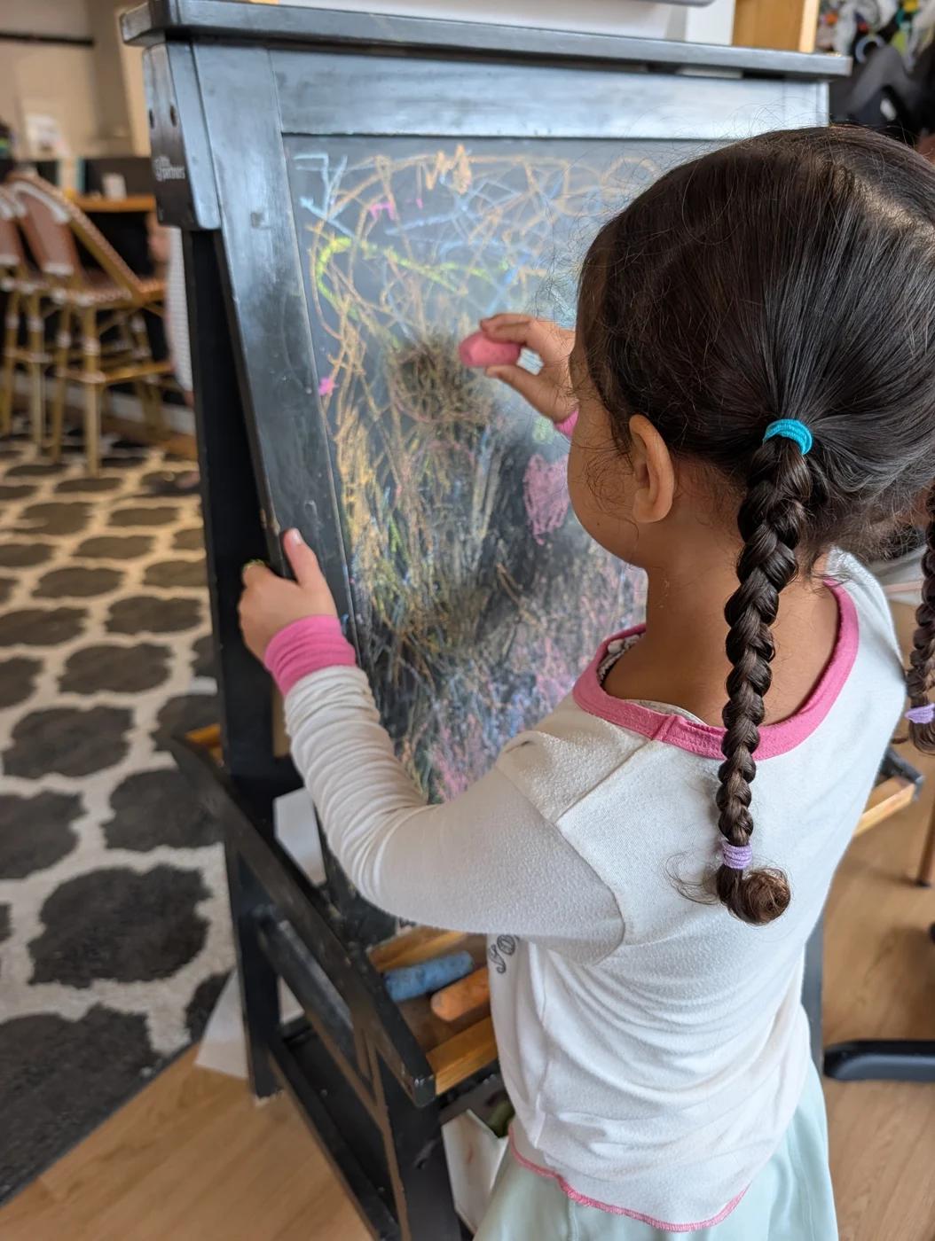 Kim’s daughter drawing with chalk on a café chalkboard during a family stop.