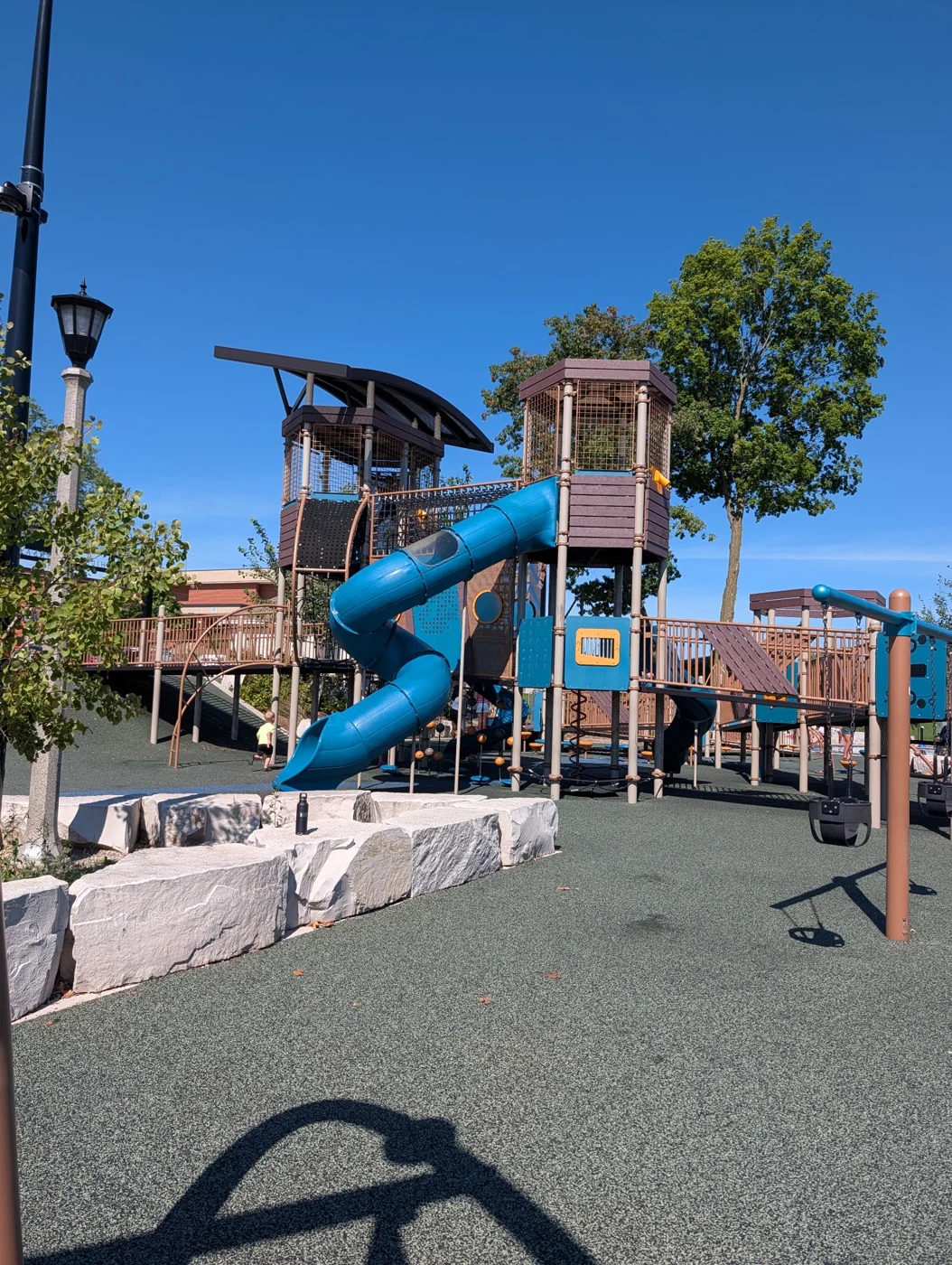 A playground with a blue tube slide and a stone border, found on one of Kim’s family trips.