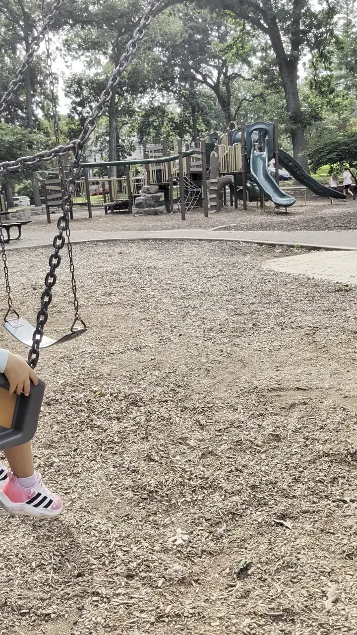 Kim’s daughter on a playground swing among the trees on one of their family trips.